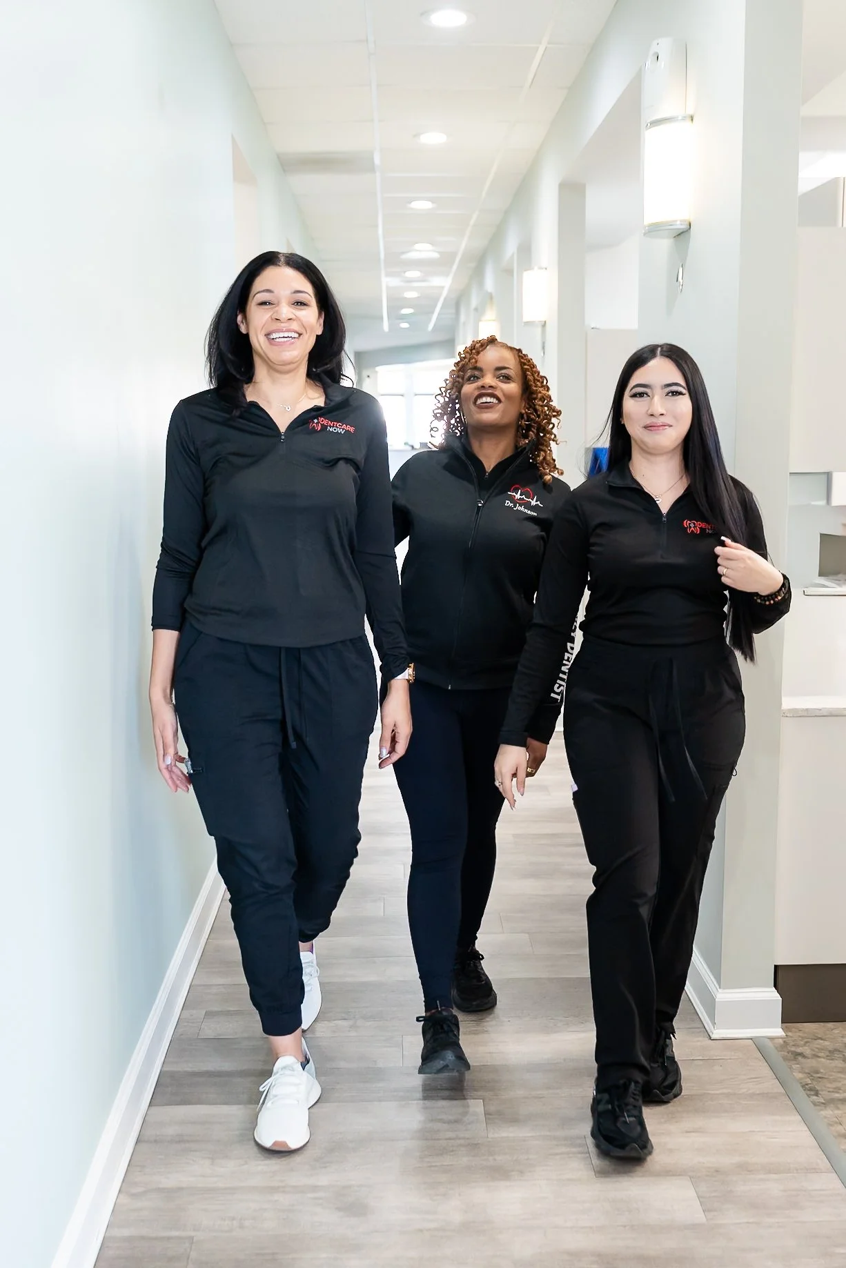 Three Dentcare Now team members walking down a bright hallway in the dental office
